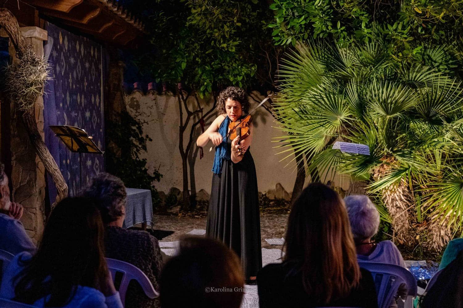 Una mujer está tocando un violín delante de una multitud de personas.