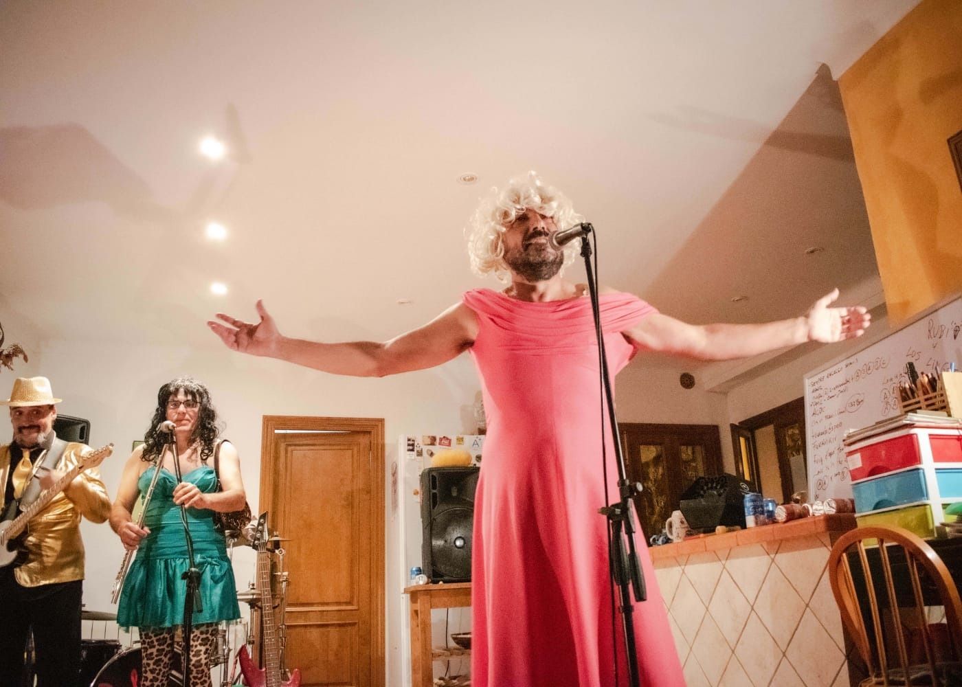 Un hombre con un vestido rosa está cantando en un micrófono.