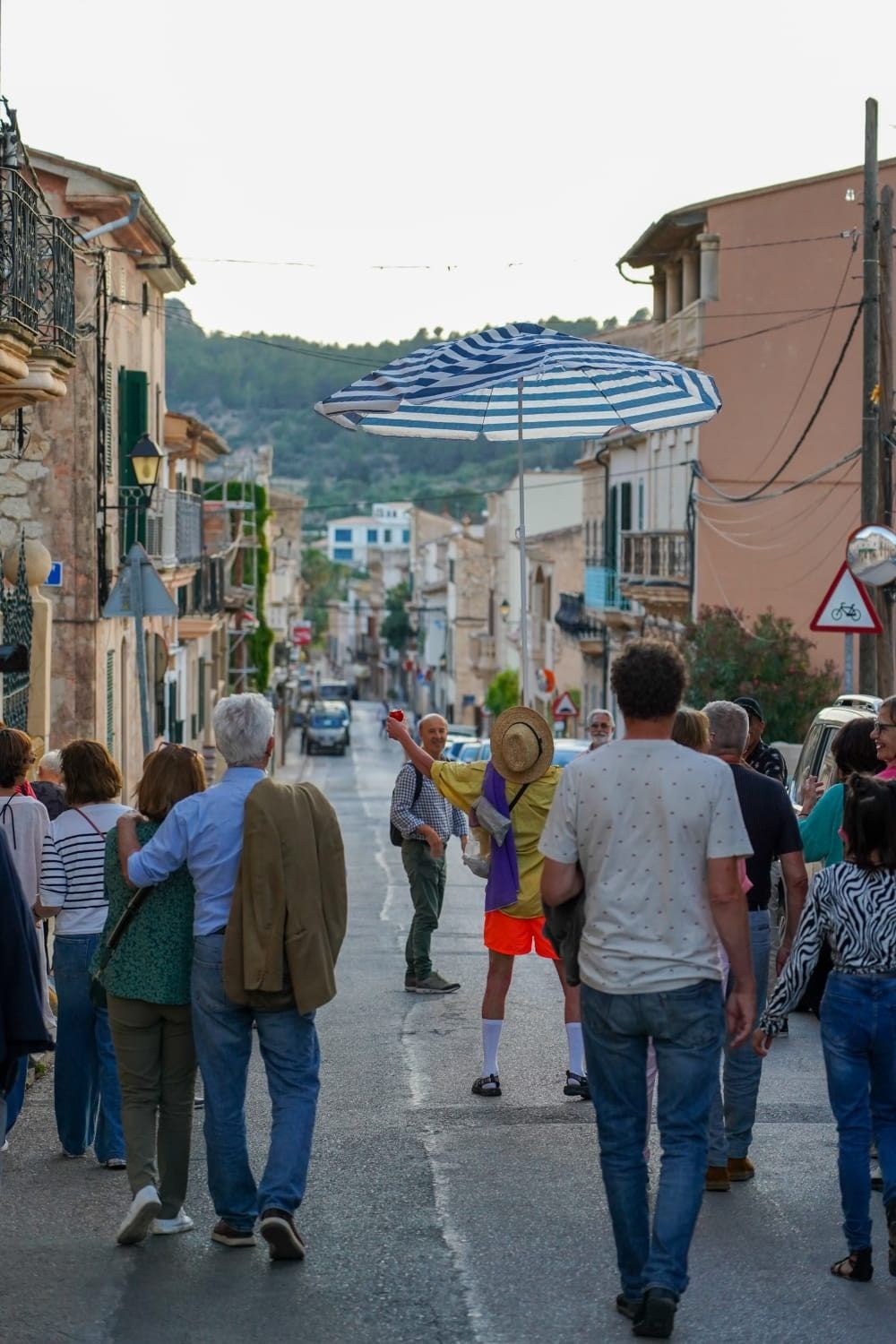 Un grupo de personas camina por una calle con un paraguas al fondo.