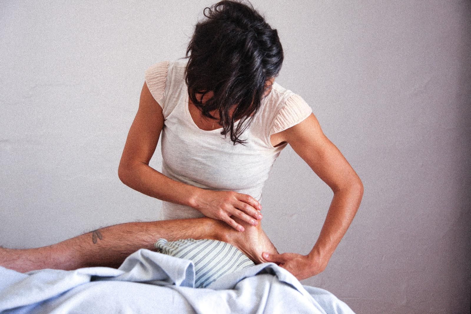 Una mujer le está dando un masaje de pies a un hombre.