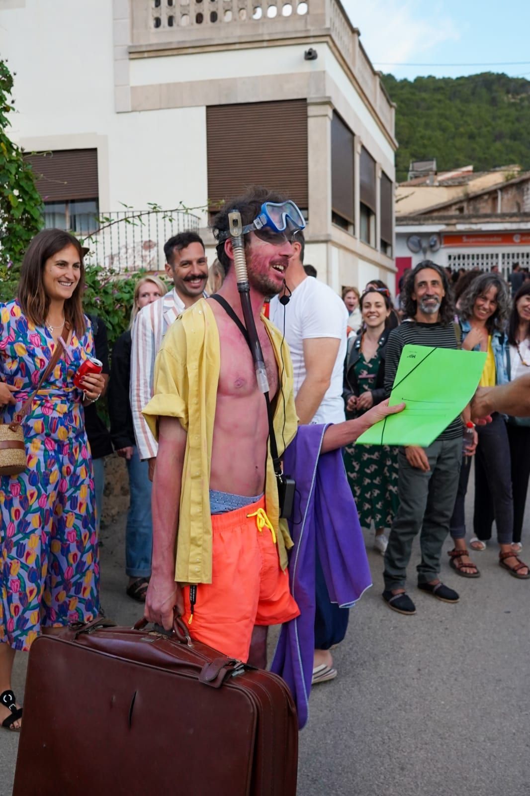 Un grupo de personas está de pie alrededor de un hombre que lleva una maleta.
