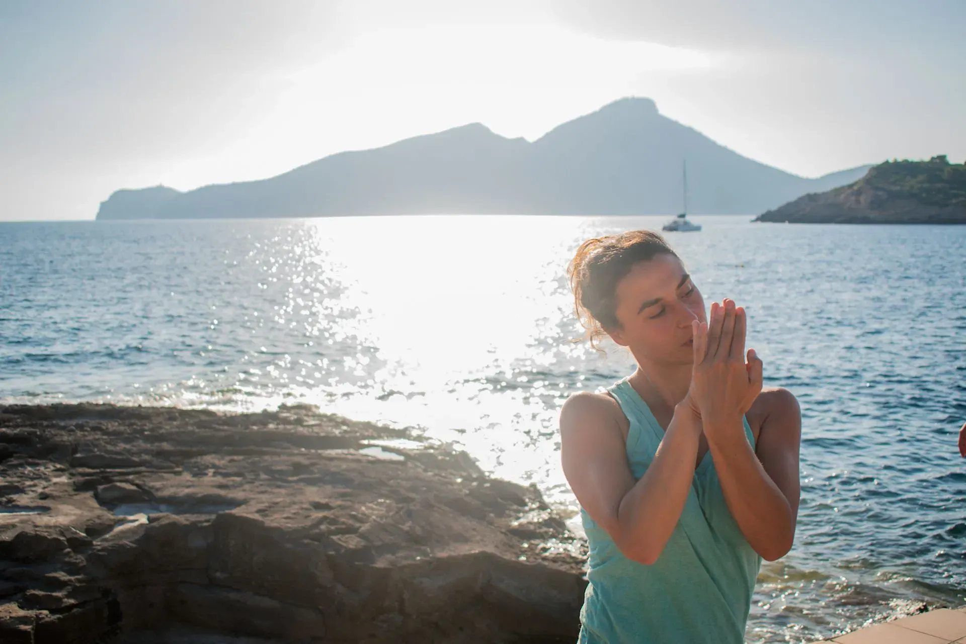 Una mujer está orando en la playa cerca del océano.