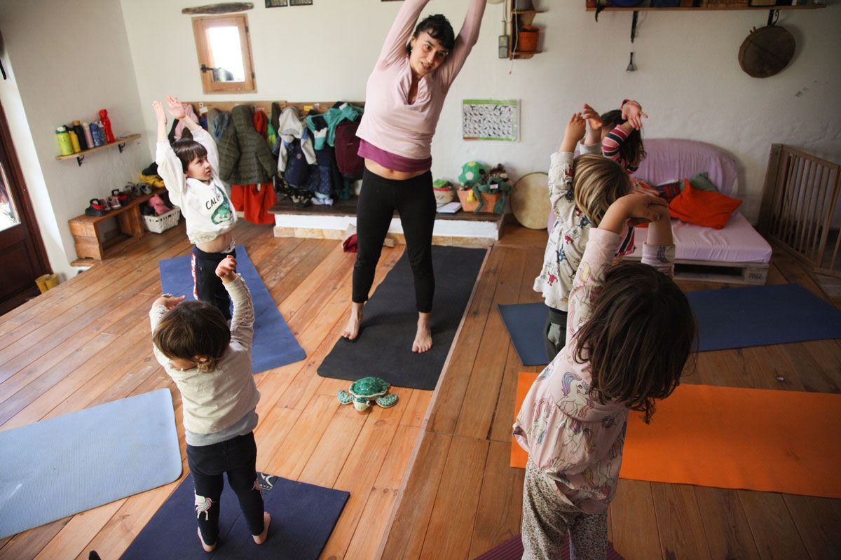 Una mujer está haciendo yoga con un grupo de niños.