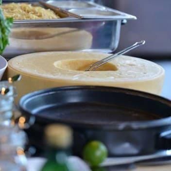 Ein großes Stück Käse liegt auf einem Tisch neben einer Schüssel Suppe.