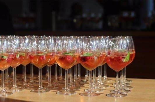 Eine Reihe von mit einem Getränk gefüllten Weingläsern auf einem Tisch.