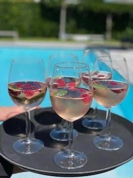Eine Person hält ein Tablett mit Weingläsern neben einem Pool.