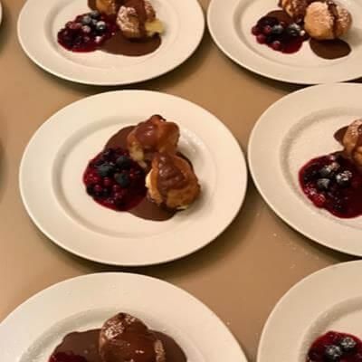 Ein Tisch voller Teller mit Desserts mit Schokoladensoße und Beeren.