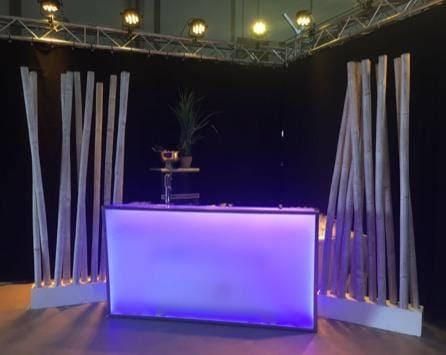 Eine Bar mit einem violetten Licht ist von Holzstäben umgeben.