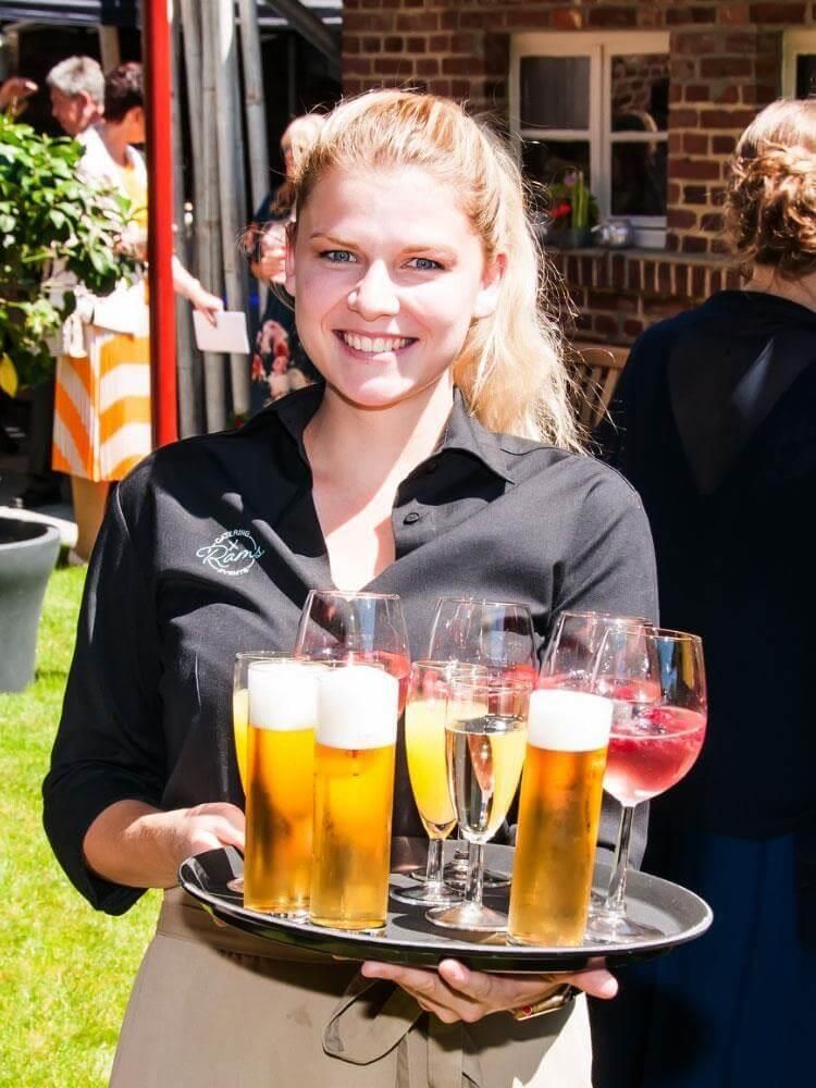 Eine Frau hält ein Tablett mit Bier und Weingläsern