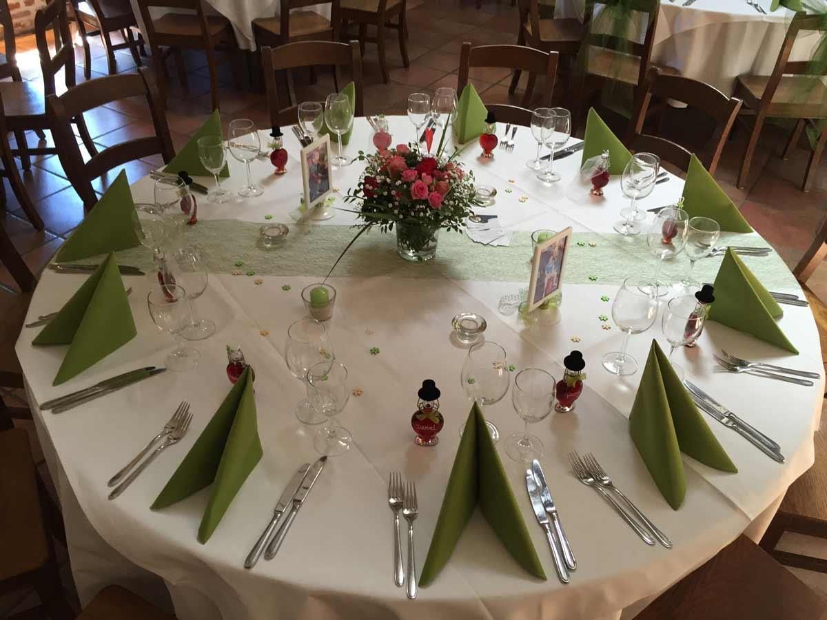 Ein runder Tisch mit grünen Servietten und Besteck darauf