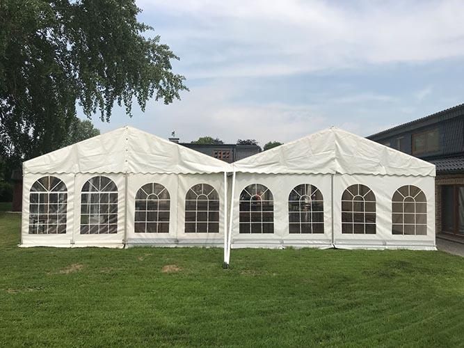 Ein großes weißes Zelt steht auf einem üppigen grünen Feld.
