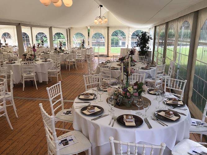 Ein großes Zelt mit Tischen und Stühlen für einen Hochzeitsempfang.