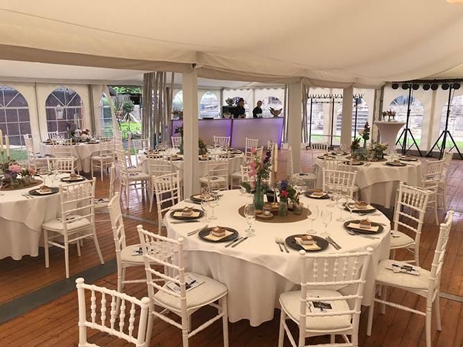 Ein großer Raum mit Tischen und Stühlen für einen Hochzeitsempfang.