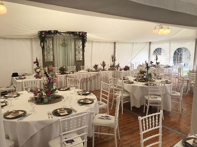 Ein großes Zelt mit Tischen und Stühlen für einen Hochzeitsempfang.