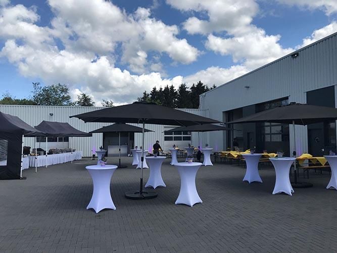 Eine Reihe von Tischen und Sonnenschirmen vor einem Gebäude.