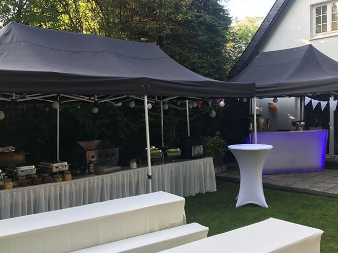 Ein Zelt mit einem Tisch darunter vor einem Haus