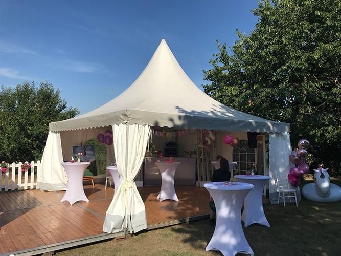 Ein weißes Zelt mit Tischen und Luftballons davor.