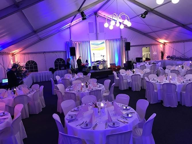 Ein großer Raum mit Tischen und Stühlen für einen Hochzeitsempfang.