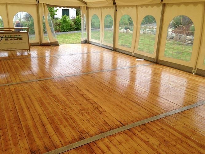 Ein großes Zelt mit einer hölzernen Tanzfläche darin.