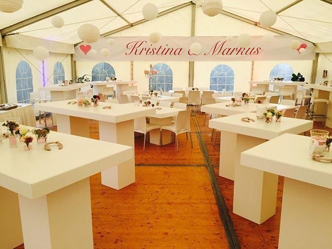 Ein Zelt mit Tischen und Stühlen und einem Banner mit der Aufschrift „Kristina und Markus“