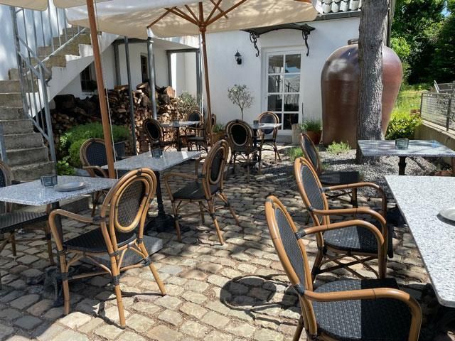 Eine Terrasse mit Tischen und Stühlen unter Sonnenschirmen