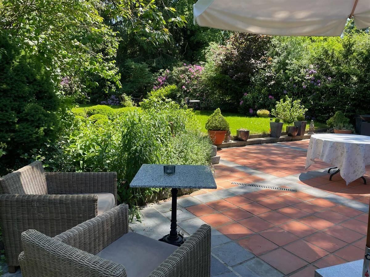 Eine Terrasse mit Stühlen und einem Tisch unter einem Sonnenschirm.