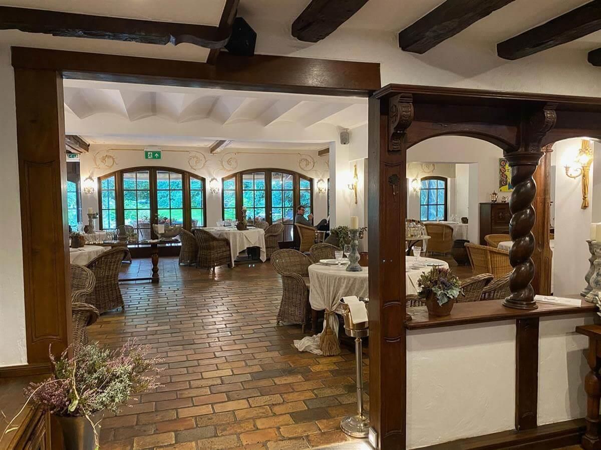 Ein großer Raum mit Tischen und Stühlen und einem Ziegelboden.