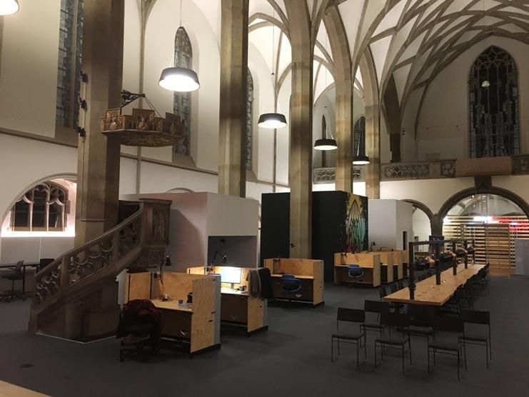 Ein großer Raum mit einer Treppe und vielen Tischen und Stühlen