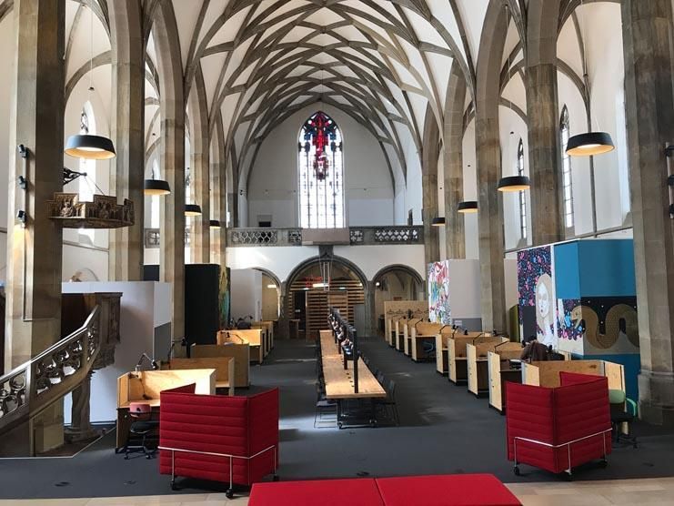 Das Innere einer Kirche mit roten Stühlen und Tischen.