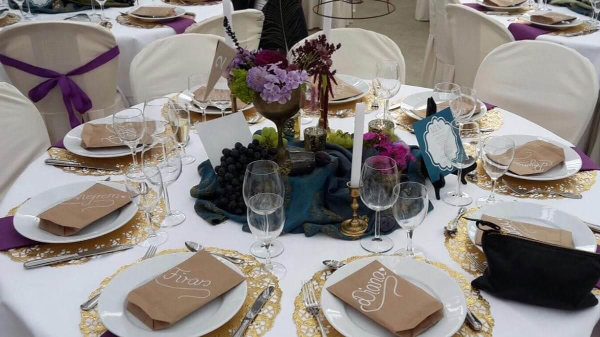 Ein für einen Hochzeitsempfang gedeckter Tisch mit Tellern, Servietten, Kerzen und einem Tafelaufsatz.