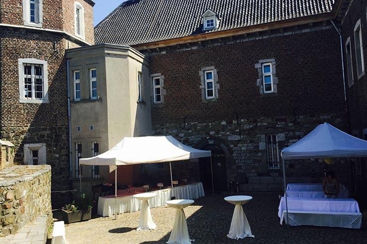 Ein Backsteingebäude mit Tischen und Zelten davor