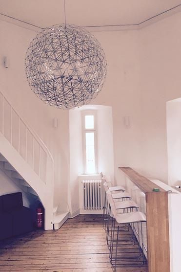 Ein Wohnzimmer mit einer Treppe und einem Kronleuchter, der von der Decke hängt.