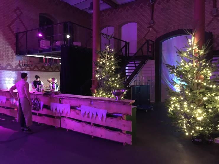 Ein Mann steht vor einer Holzbar mit Weihnachtsbäumen im Hintergrund.