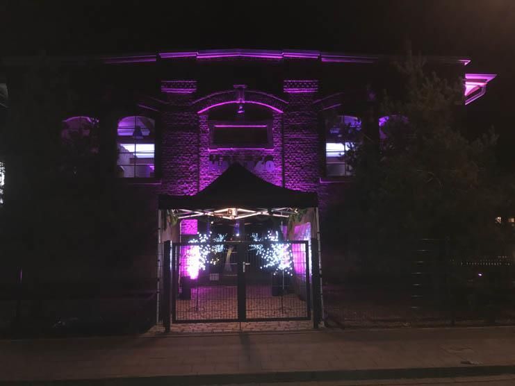 Ein Gebäude mit violetten Lichtern ist nachts beleuchtet.