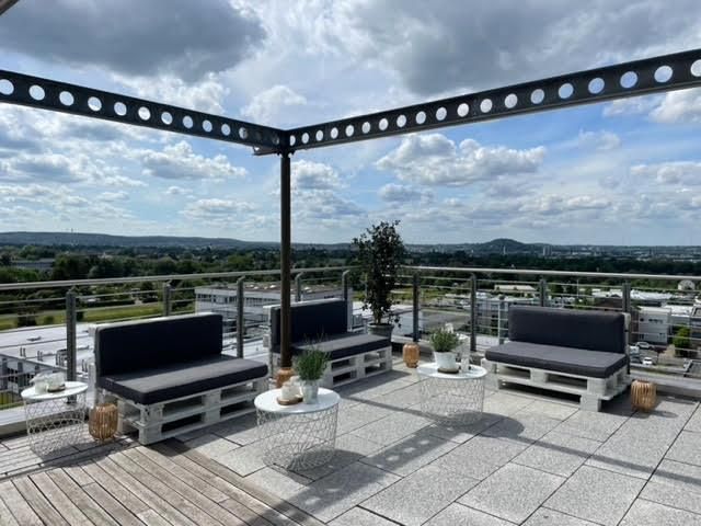 Auf dem Dach eines Gebäudes stehen viele Stühle und Tische.