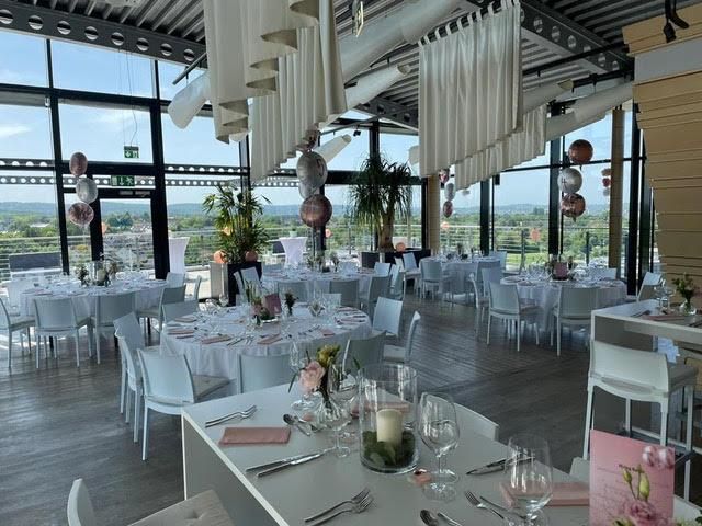 Ein großer Raum mit Tischen und Stühlen für einen Hochzeitsempfang.