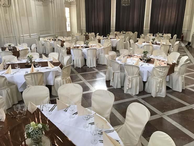 Ein großer Raum mit Tischen und Stühlen für einen Hochzeitsempfang.