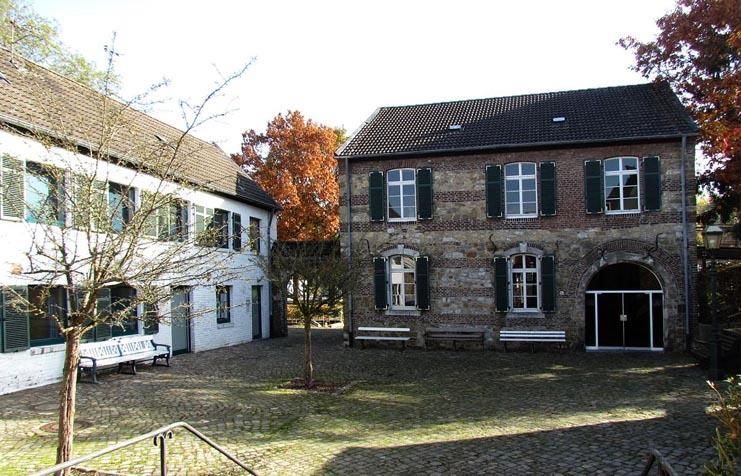 Ein Backsteingebäude mit schwarzen Fensterläden steht neben einem weißen Gebäude