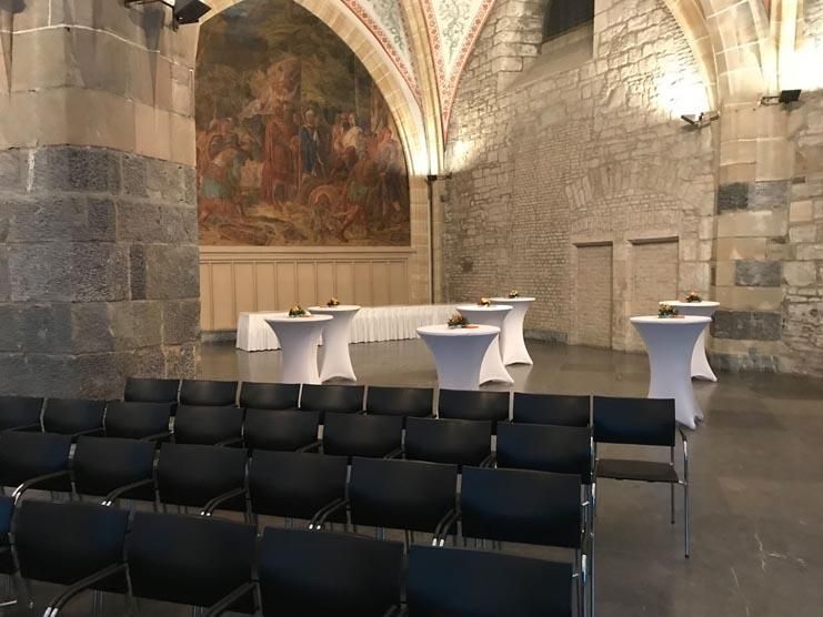 Ein Raum mit Tischen und Stühlen und einem Gemälde an der Wand.