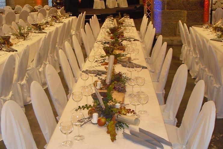 Ein langer Tisch mit weißen Stühlen und Blumen darauf