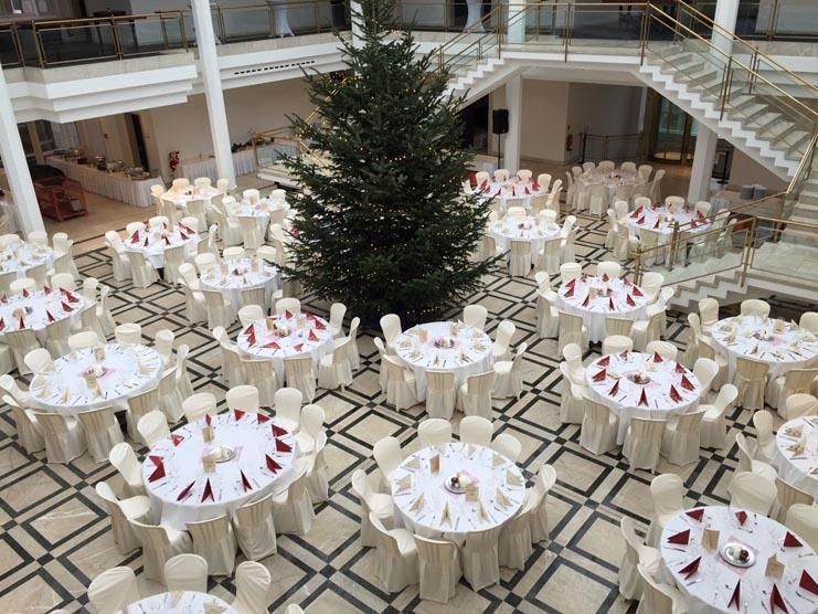 Ein großer Raum mit Tischen und Stühlen und einem Weihnachtsbaum in der Mitte.