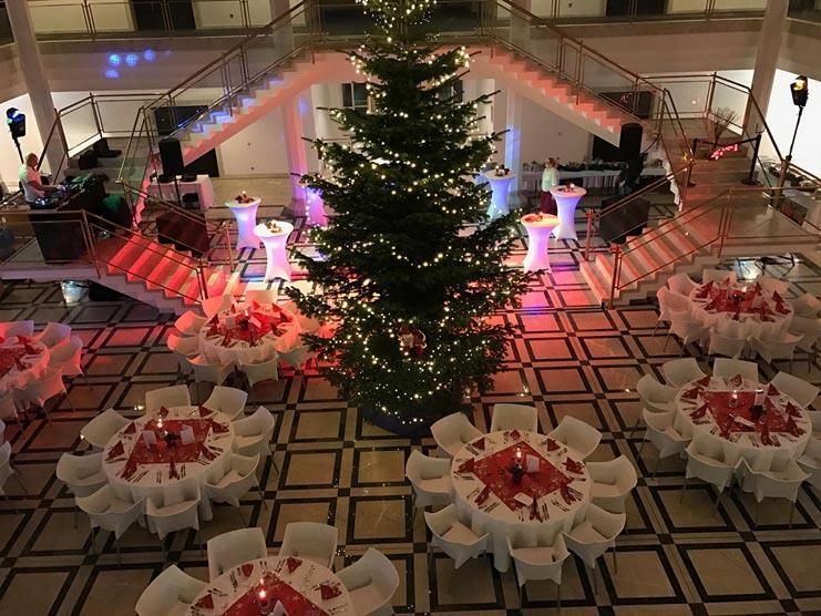 Ein großer Weihnachtsbaum steht in der Mitte eines Raumes voller Tische und Stühle