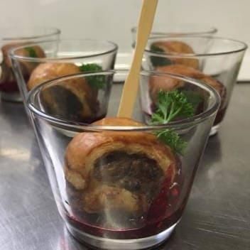 Ein mit Essen gefülltes Glas mit einem Holzlöffel darin.