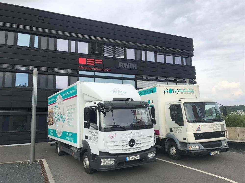 Zwei Lastwagen parken vor einem Gebäude.