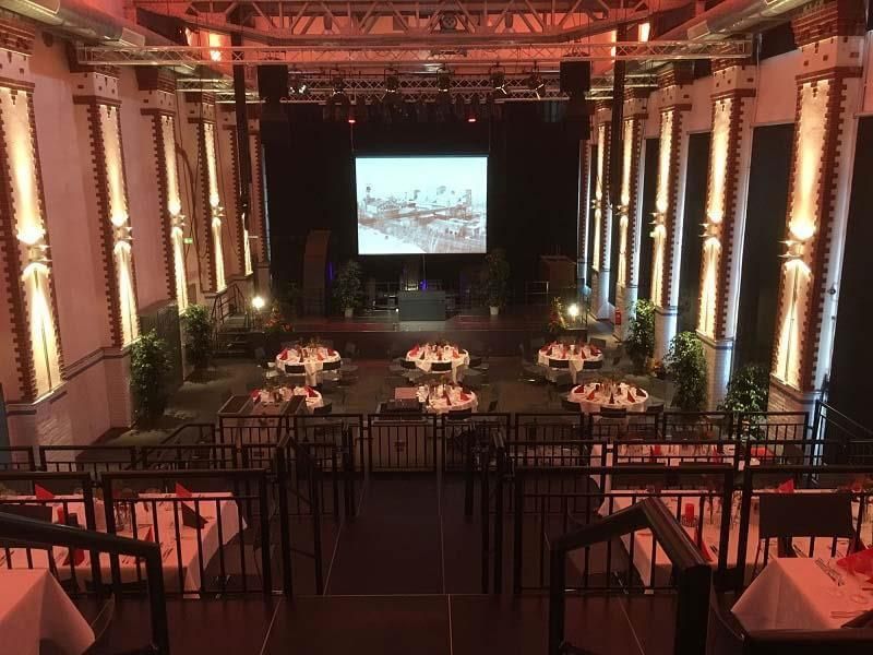 Ein großer Raum mit Tischen und Stühlen und einer großen Leinwand auf der Bühne