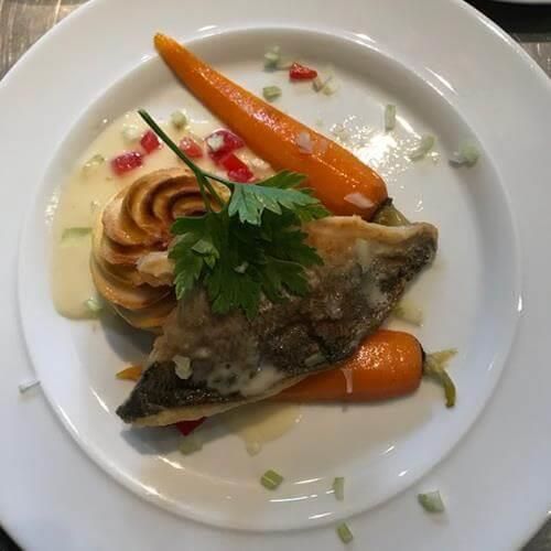 Ein weißer Teller mit einem Stück Fisch und Karotten