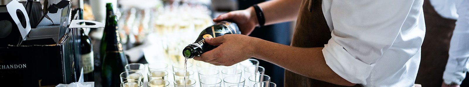 Ein Barkeeper gießt eine Flasche Champagner in ein Glas.