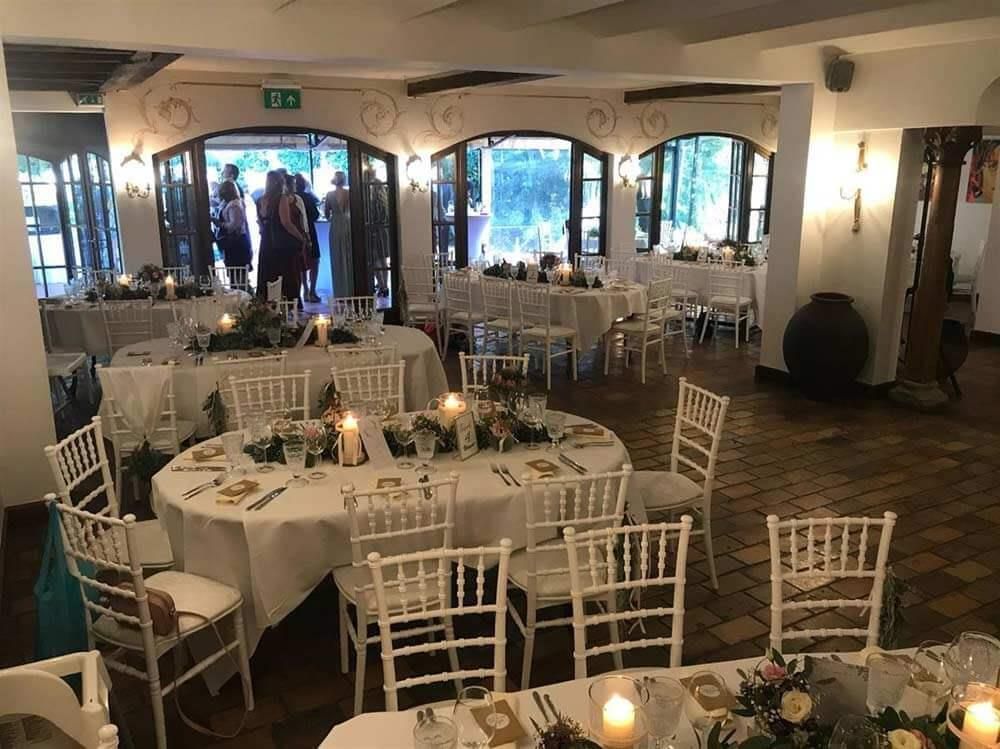 Ein großer Raum mit Tischen und Stühlen für einen Hochzeitsempfang.