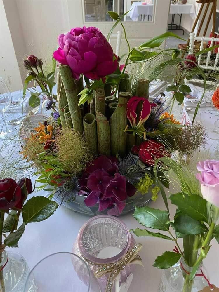 Ein Tisch mit einer Blumenvase und Kerzen darauf.