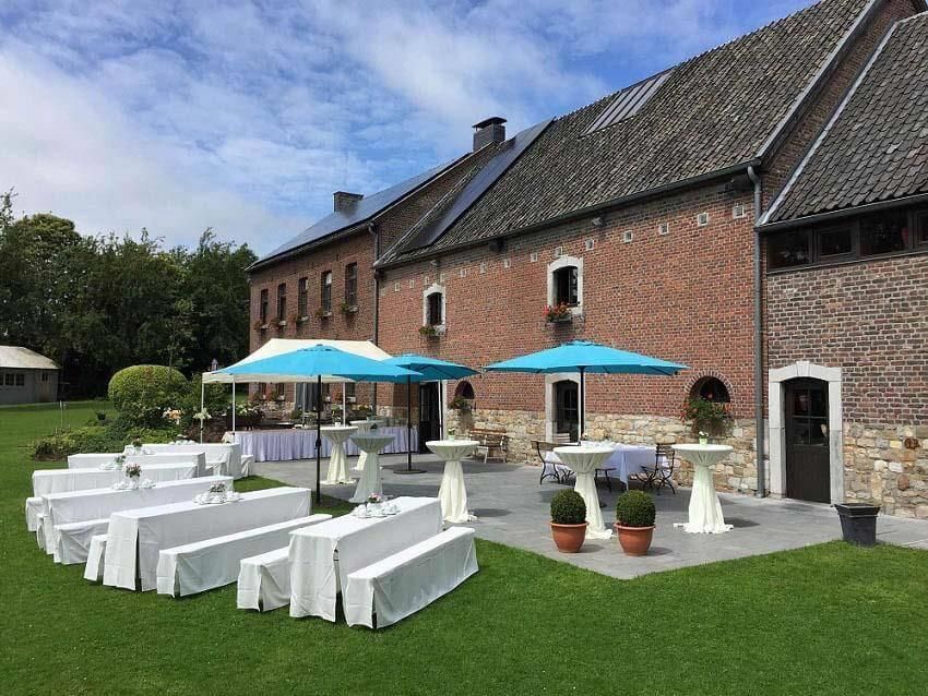 Ein großes Backsteingebäude mit Tischen und Sonnenschirmen davor